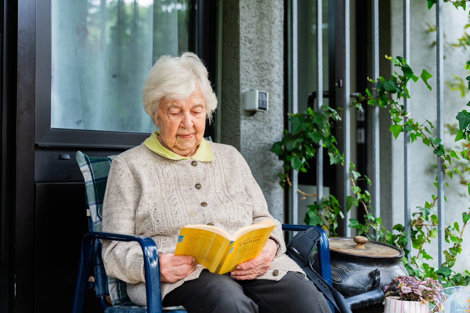 Bewohnerin des Olgahauses liest ein Buch auf ihrem Balkon