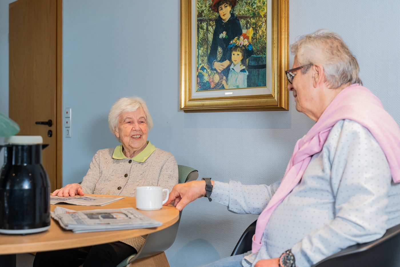 Zwei Bewohnerinnen im Gespräch bei Kaffee und Zeitung