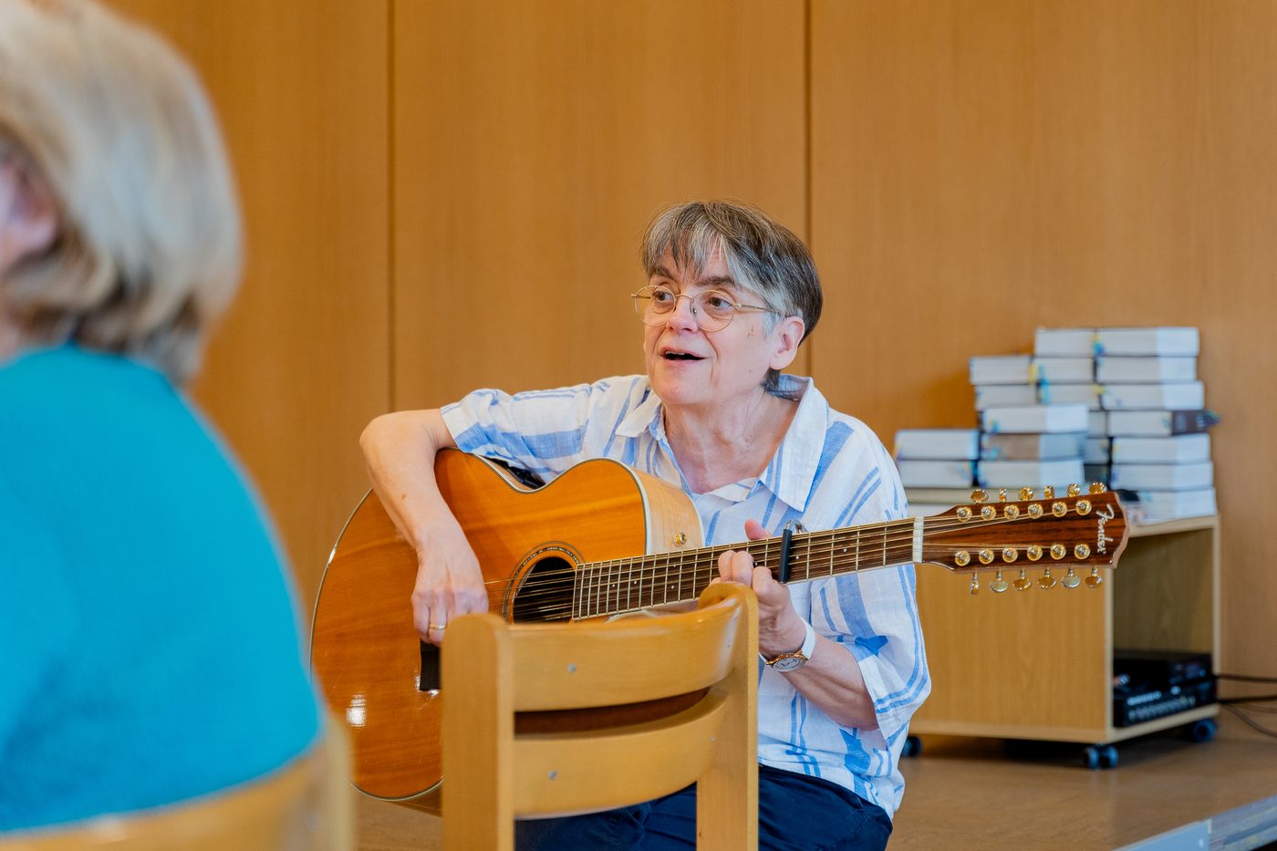 Eine Frau begleitet den Singkreis mit der Gitarre